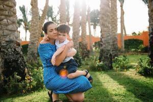 Stylish mother and handsome son having fun on a green lawn. Happy family concept. Beauty nature scene with family outdoor lifestyle. Happy family resting together. Mothers day photo