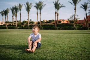 Cute boy runs on a green lawn playing catch-up in nature on a Sunny day. photo