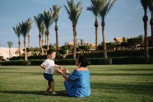 Stylish mother and handsome son having fun on a green lawn. Happy family concept. Beauty nature scene with family outdoor lifestyle. Happy family resting together. Mothers day photo