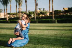 Stylish mother and handsome son having fun on a green lawn. Happy family concept. Beauty nature scene with family outdoor lifestyle. Happy family resting together. Mothers day photo