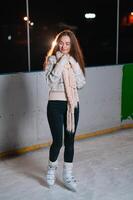 retrato joven sonriente mujer en blanco sombrero con patines en hielo pista foto