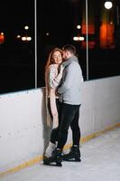 tema hielo Patinaje pista y amoroso Pareja. reunión joven, elegante personas paseo por mano en multitud en ciudad Patinaje pista iluminado por ligero bombillas y luces. hielo Patinaje en invierno para Navidad en hielo arena. foto