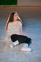 Portrait young smiling woman in white hat with skates on ice rink photo