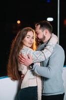 Romantic couple on date. Young couple standing together outdoors on open ice rink in snowy winter landscape photo