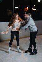 invierno patines, amoroso Pareja participación manos y laminación en pista. iluminación en fondo, noche. concepto capacitación. foto