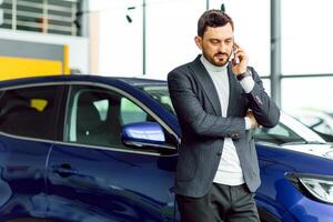 business, car sale, consumerism and people concept - happy man over auto show or salon background photo