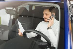 Attractive handsome young businessman using mobile smart phone in car. photo