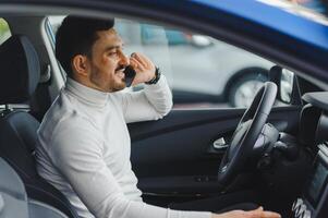 hermoso barbado empresario es sentado en un nuevo coche en coche concesión foto