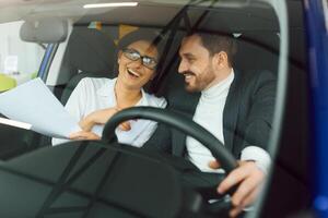 Handsome bearded businessman is sitting in a new car in car dealership photo