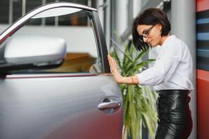 Young girl dreaming of a new car inspecting a new white car at a car dealership, for further purchase on credit photo