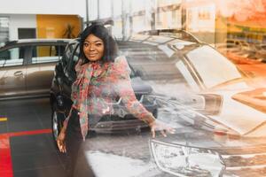 beautiful young african woman buying a car at dealership photo