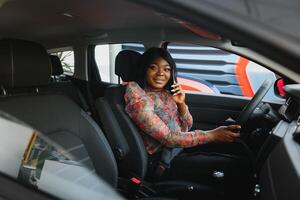 Beautiful young mixed race black African American woman driving car and speaks by phone photo