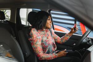 hermosa joven mezclado carrera negro africano americano mujer conducción coche y habla por teléfono foto