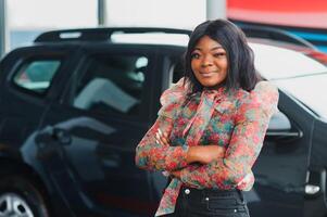 Women buying the car. Ladies in a car salon. Black girls near white car photo