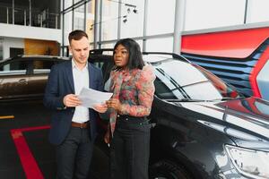 beautiful young african woman buying a car at dealership photo