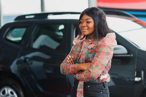 Women buying the car. Ladies in a car salon. Black girls near white car photo