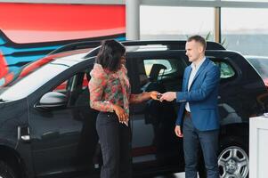 beautiful young african woman buying a car at dealership photo