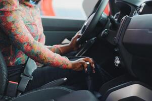 Woman driving. Driver holding hand on transmission and steering wheel. Owner starting her car. Close-up photo