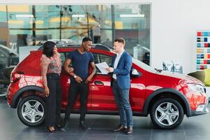 happy african couple choosing luxury car at vehicle dealership looking at the interior photo