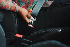 Dark brown skin African woman hand buckling safety belt in the car for automobile accident safety concept photo