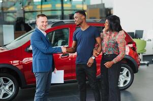 happy woman receiving a new car from her husband at dealership photo