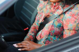 Dark brown skin African woman hand buckling safety belt in the car for automobile accident safety concept photo