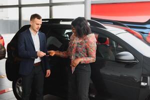 Woman buying the car. Lady in a car salon. Elegant black girl photo