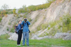 caminantes con mochilas relajante en parte superior de un colina y disfrutando ver de puesta de sol en océano. isla lombok, Indonesia. de viaje a lo largo montañas y costa, libertad y activo estilo de vida concepto foto