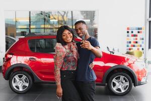 happy african couple choosing luxury car at vehicle dealership looking at the interior photo