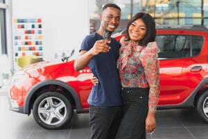 happy african couple choosing luxury car at vehicle dealership looking at the interior photo