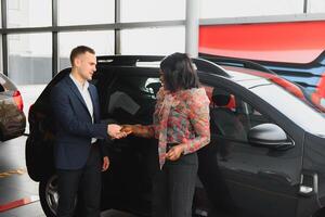 beautiful african american woman buying a car at dealership photo