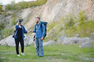 Couple enjoying beautiful views on the mountains, while traveling with backpacks in the mountains during the summer vacations photo