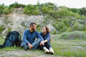 Couple enjoying beautiful views on the mountains, while traveling with backpacks in the mountains during the summer vacations photo