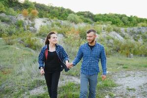 Couple enjoying beautiful views on the mountains, while traveling with backpacks in the mountains during the summer vacations photo