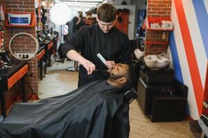 Black man in the barbershop. Cute black man makes a haircut in the African salon. Hair style. Haircut for adults. photo