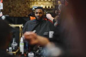 Black man in the barbershop. Cute black man makes a haircut in the African salon. Hair style. Haircut for adults. photo