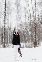 joven elegante mujer con un perro teniendo divertido en un invierno bosque. foto