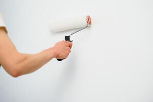 The painter is painting a wall in a room with a roller. photo