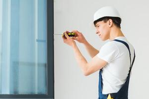 Young handyman repair window with screwdriver photo