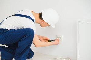 Electrician installs decorative frame on electric and TV sockets. photo