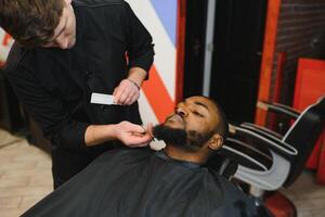 visitando peluquería. africano americano hombre en un elegante Barbero tienda foto