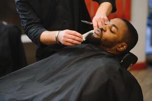 African male client getting haircut at barber shop from professional hairstylist. photo