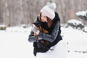 Young stylish woman with a dog having fun in a winter forest. photo