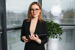 Portrait of middle age businesswoman standing with digital tablet at office. Business people. photo