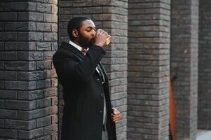 Young african american businessman drinking take away coffee at the city. photo