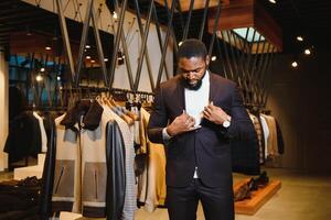 un elegante esmeradamente vestido afroamericano hombre trabajando a clásico ropa de caballero almacenar. foto