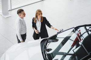 Young couple byuing a car in a car showroom. photo