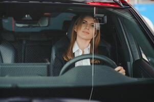 foto de contento joven mujer sentado dentro su nuevo coche. concepto para coche alquiler.