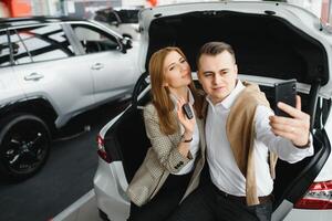 Family selfie in dealership. Happy young couple chooses and buying a new car for the family photo