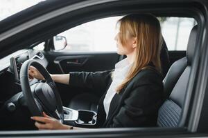 Young beautiful woman showing her love to a car in a car showroom. photo